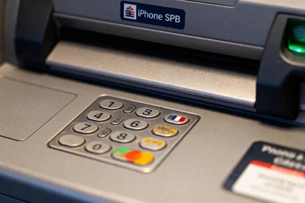 Clavier de distributeur automatique avec logos de cartes bancaires et drapeau français, marque iPhone SPB visible.