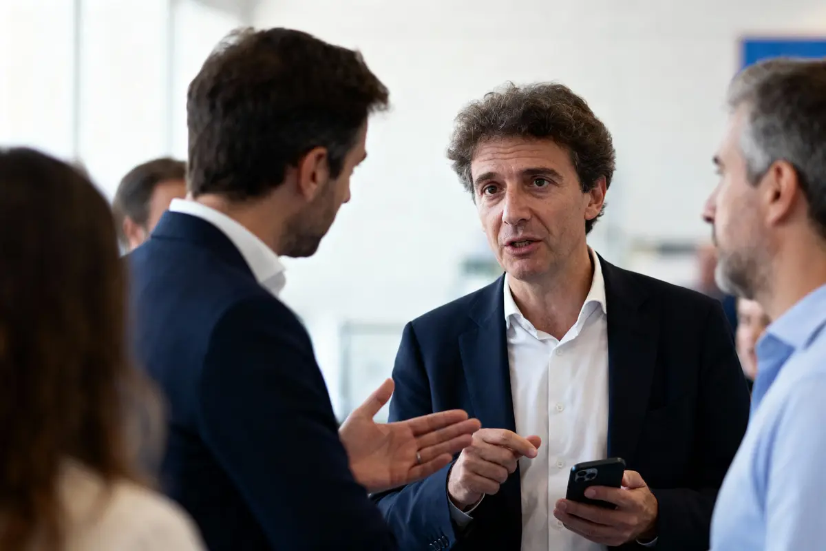 Conversation entre plusieurs hommes en tenue formelle, échangeant des idées, téléphone à la main, en intérieur.