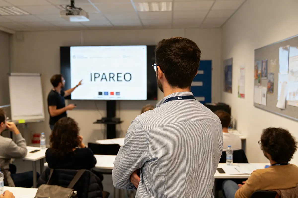 Groupe de personnes en classe, présentation IPAREO, écran, homme expliquant, ambiance professionnelle, réunion, apprentissage.