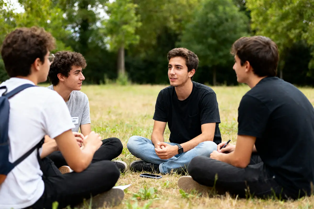 Jeunes discutant en cercle dans un parc, partageant leur envie d'entreprendre ensemble