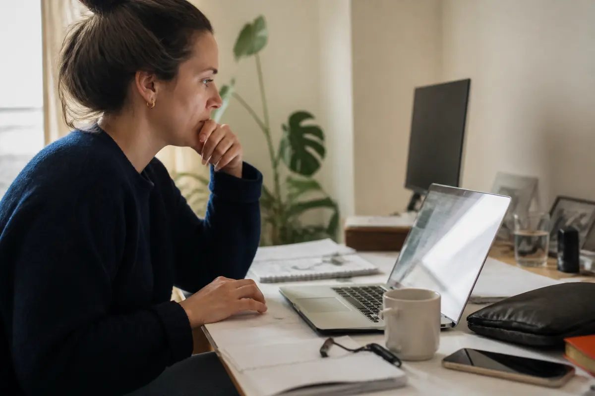 Femme concentrée sur ordinateur portable, travaillant à domicile avec détermination et efficacité